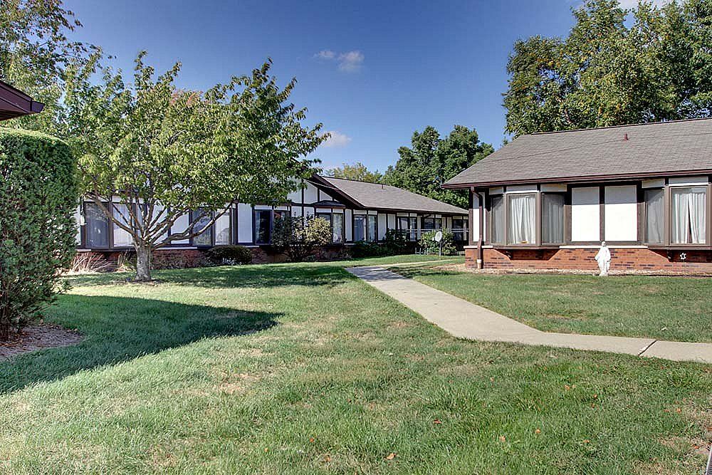 A serene suburban neighborhood with well-maintained lawns and cozy homes under a clear blue sky.
