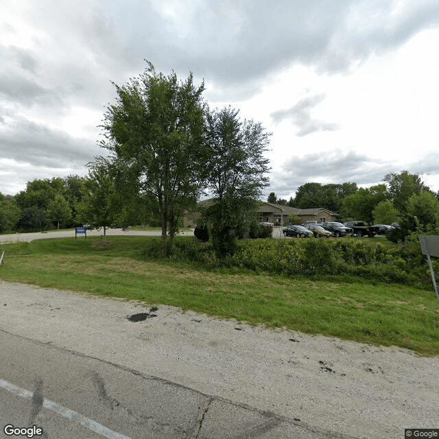A suburban street with trees and a cloudy sky.