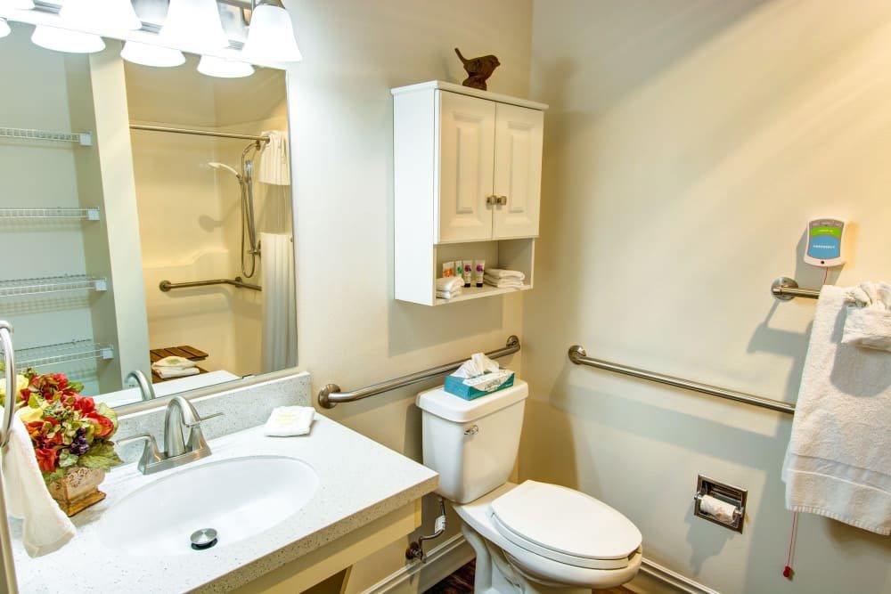 A clean and well-organized bathroom with a sink, toilet, mirror, and storage cabinet.