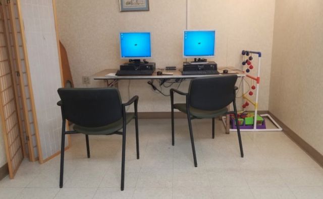 A small workstation with two computers and chairs in an office setting.