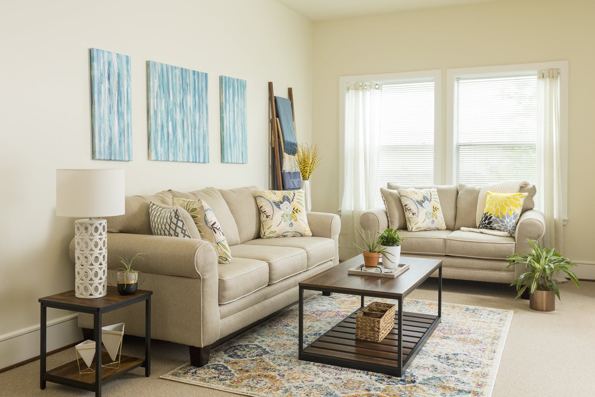 A cozy living room featuring beige sofas, a wooden coffee table, and abstract artwork on the wall.