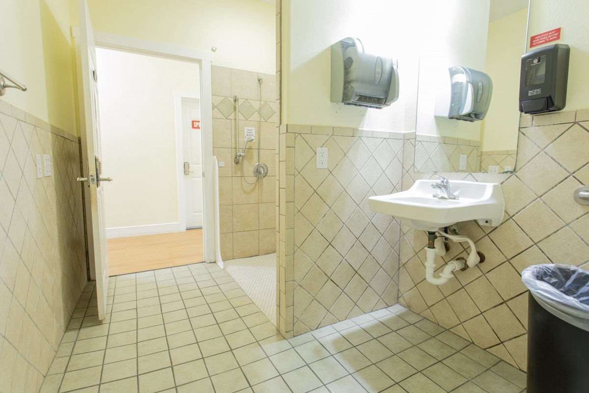 A clean public bathroom featuring a sink, hand dryers, and tiled walls and floors.
