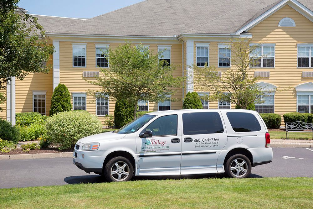 A white van parked in front of a yellow building on a sunny day.
