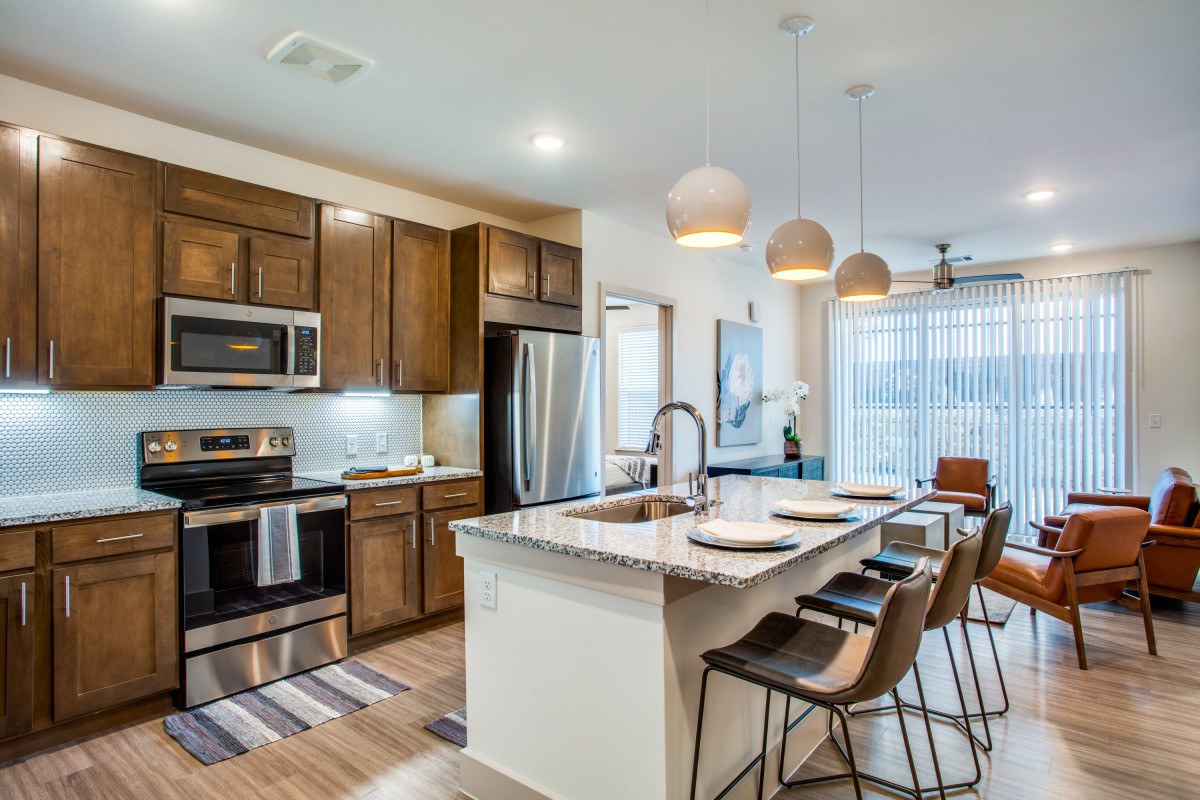 A modern kitchen with an island, featuring wood cabinets and stainless steel appliances.