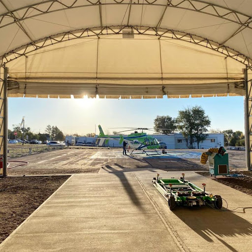 A view of a helicopter at sunrise from inside a hangar.