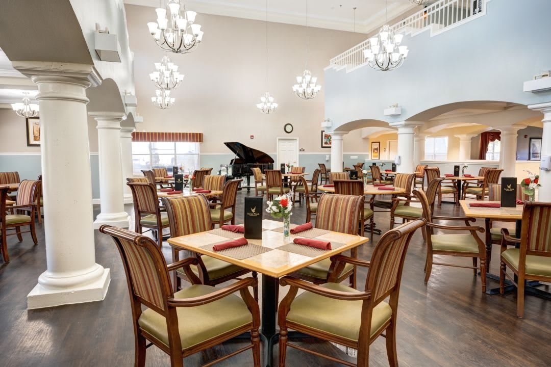 An elegant dining area featuring neatly arranged tables and chairs, illuminated by chandeliers.