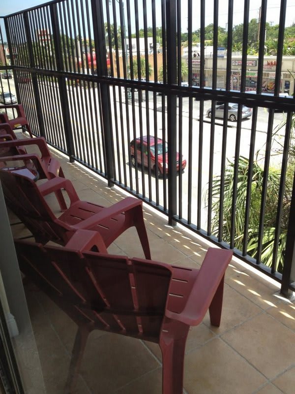 A balcony with red chairs overlooking a street.