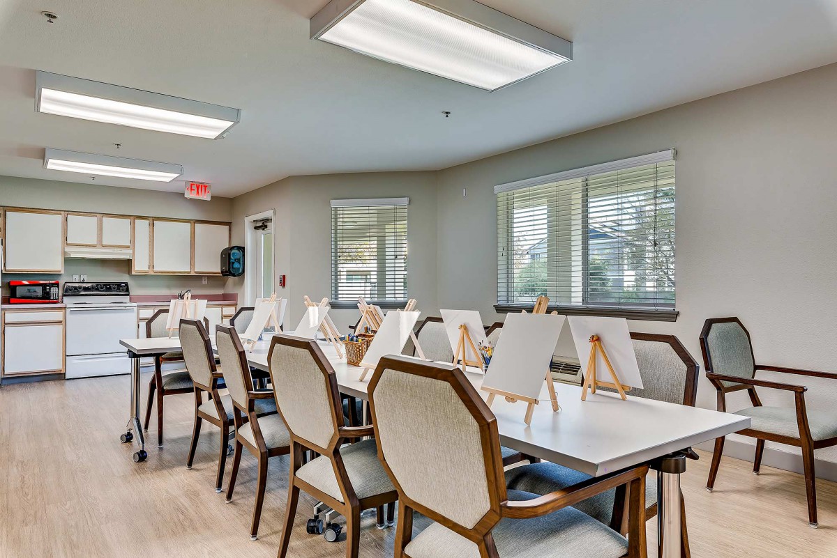 An art classroom equipped with tables, chairs, and easels, well-lit by natural and artificial lighting.