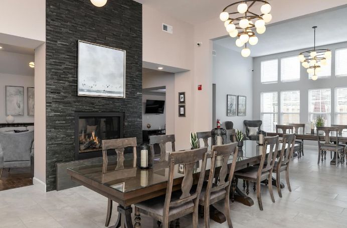 A modern dining room with a large table, chairs, and a stylish chandelier.