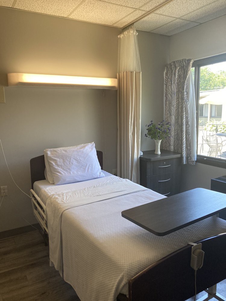 A clean and organized hospital room with a single patient bed by a window.
