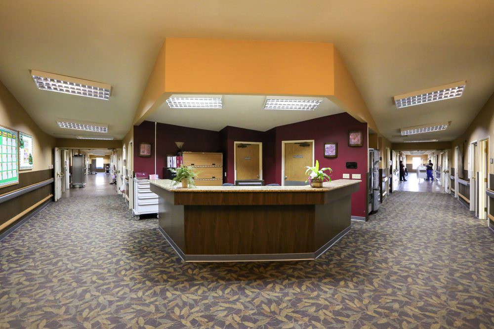 A spacious office lobby with a central reception desk and hallways extending to the sides.