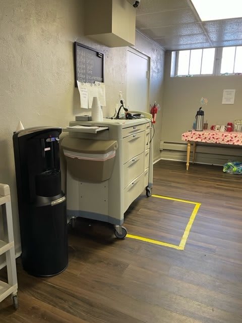 An office break area with a water cooler, cart, and coffee station.