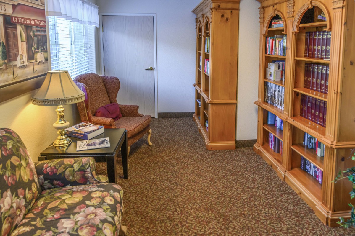 A cozy reading area with bookshelves, an armchair, and a lamp.
