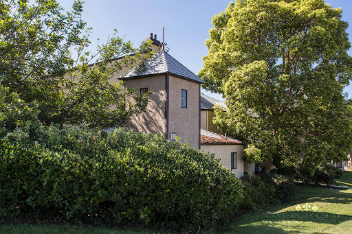 A quaint house nestled among lush greenery, surrounded by trees and a vibrant garden.