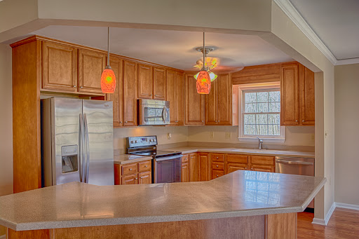 A sleek and modern kitchen featuring wooden cabinetry and stainless steel appliances, illuminated by stylish pendant lights.