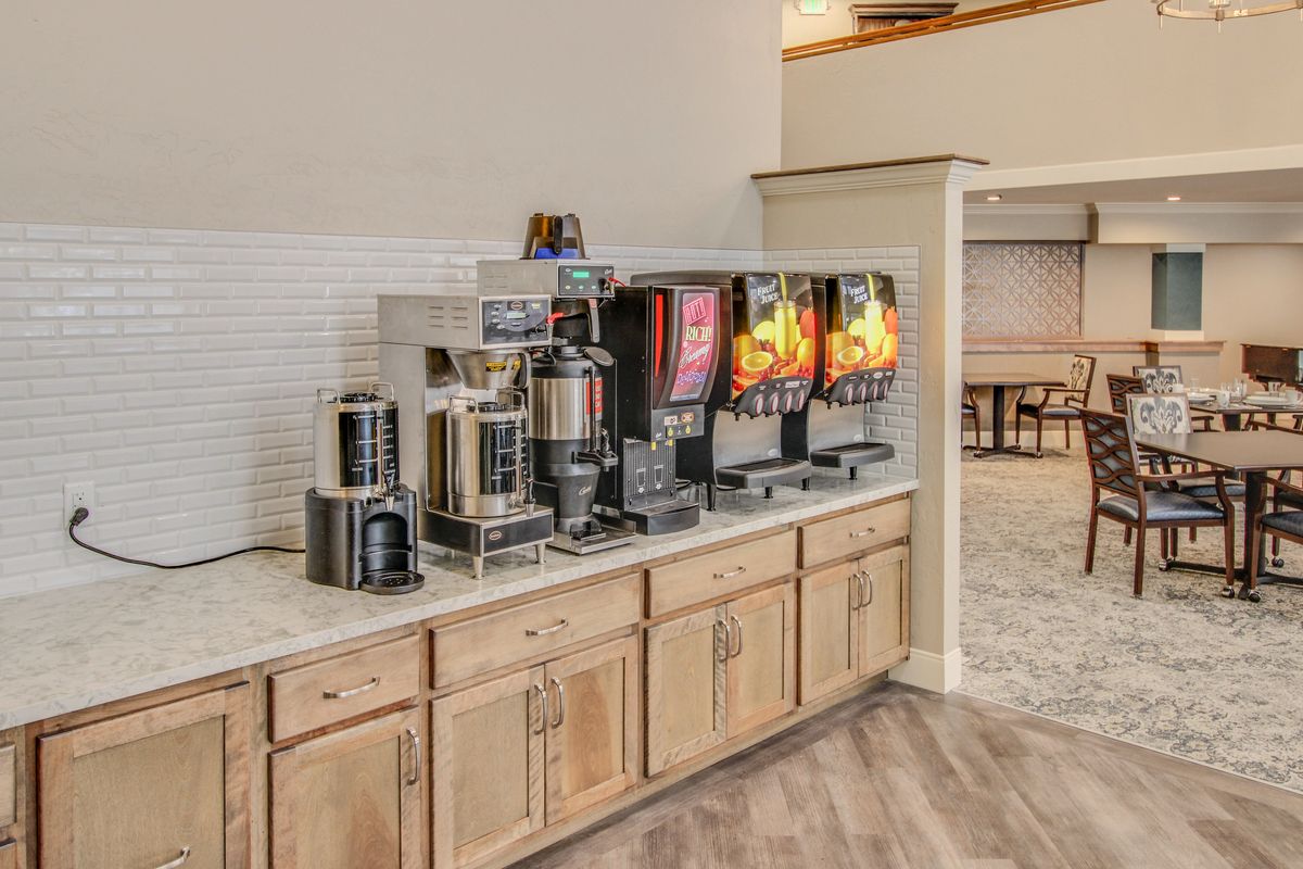 A well-equipped beverage station with coffee makers and juice dispensers in a hospitality area.