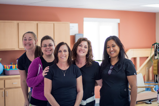 A group of professional women posing together, all smiles in casual attire.