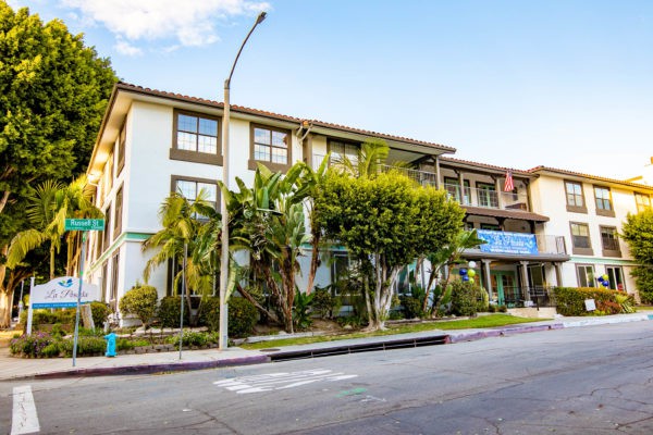 A three-story building with lush greenery along a quiet urban street.