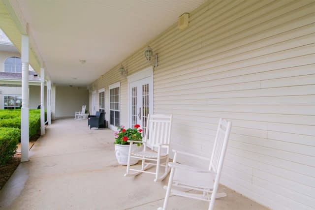 A peaceful porch with white rocking chairs and potted plants.