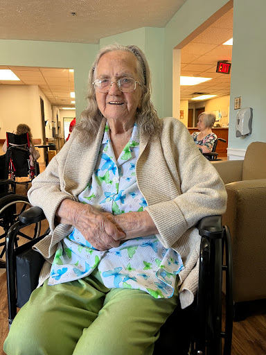 An elderly woman sitting comfortably in her wheelchair, smiling warmly.