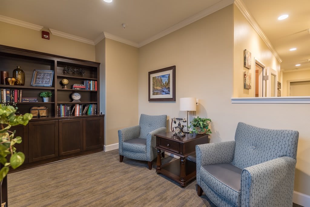 A cozy living room with two armchairs, a wooden bookshelf, and decorative items.