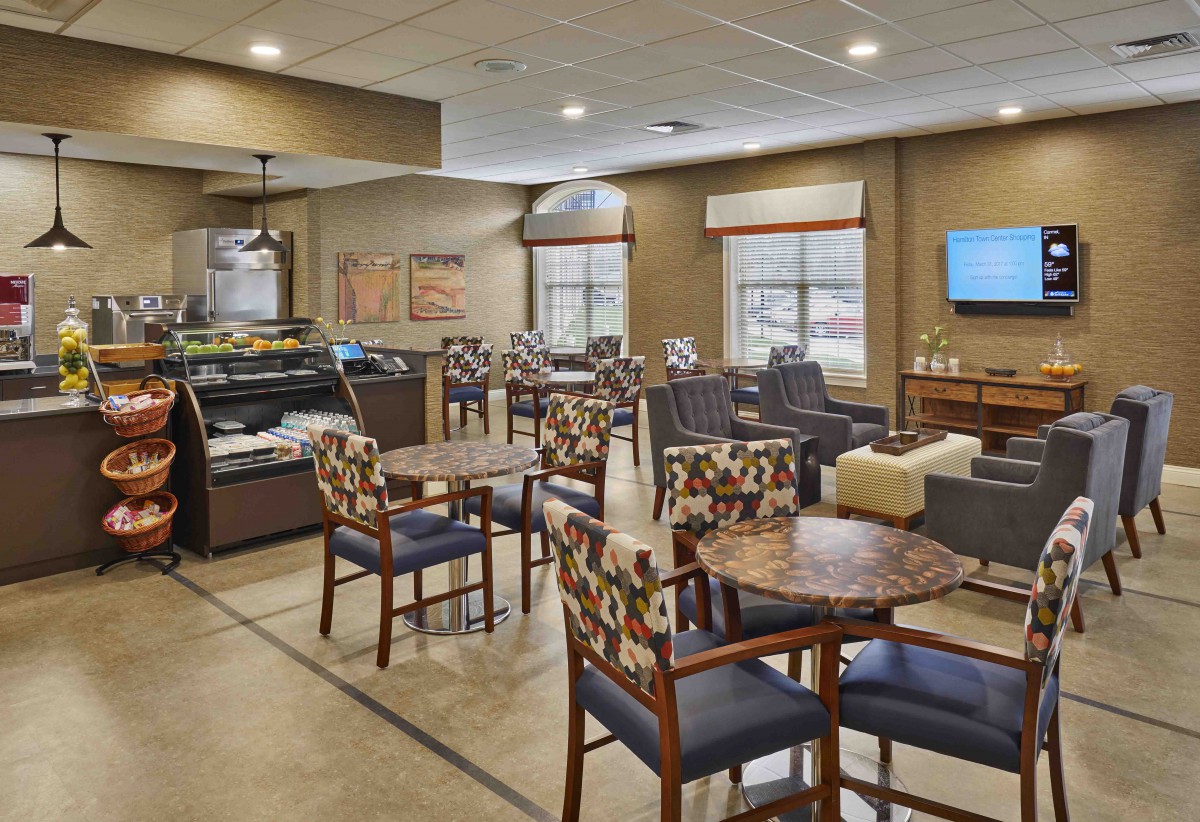 A modern cafe interior with tables and chairs arranged in a cozy seating area.