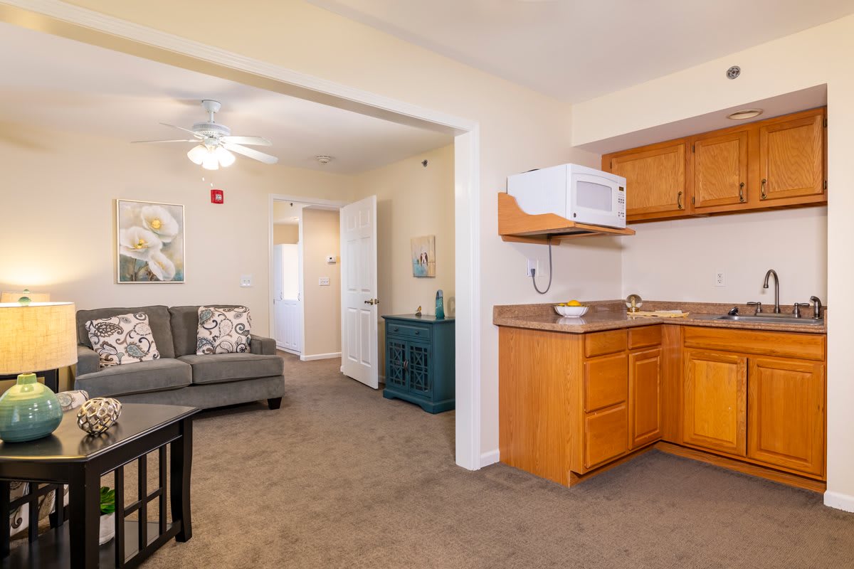 A cozy apartment interior featuring a living room with a sofa and a small kitchen area.
