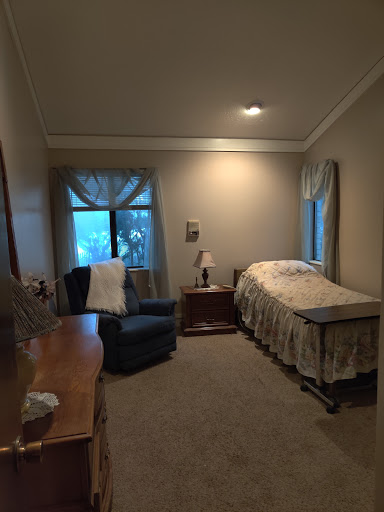 A cozy and serene bedroom featuring a bed, armchair, and gentle lighting.