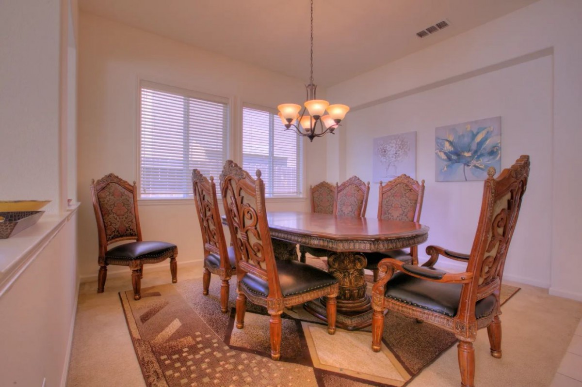 A classic dining room with ornate chairs and a central chandelier.