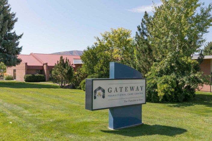 A sign for Gateway Rehabilitation Center set in a landscaped outdoor area with trees and grass.