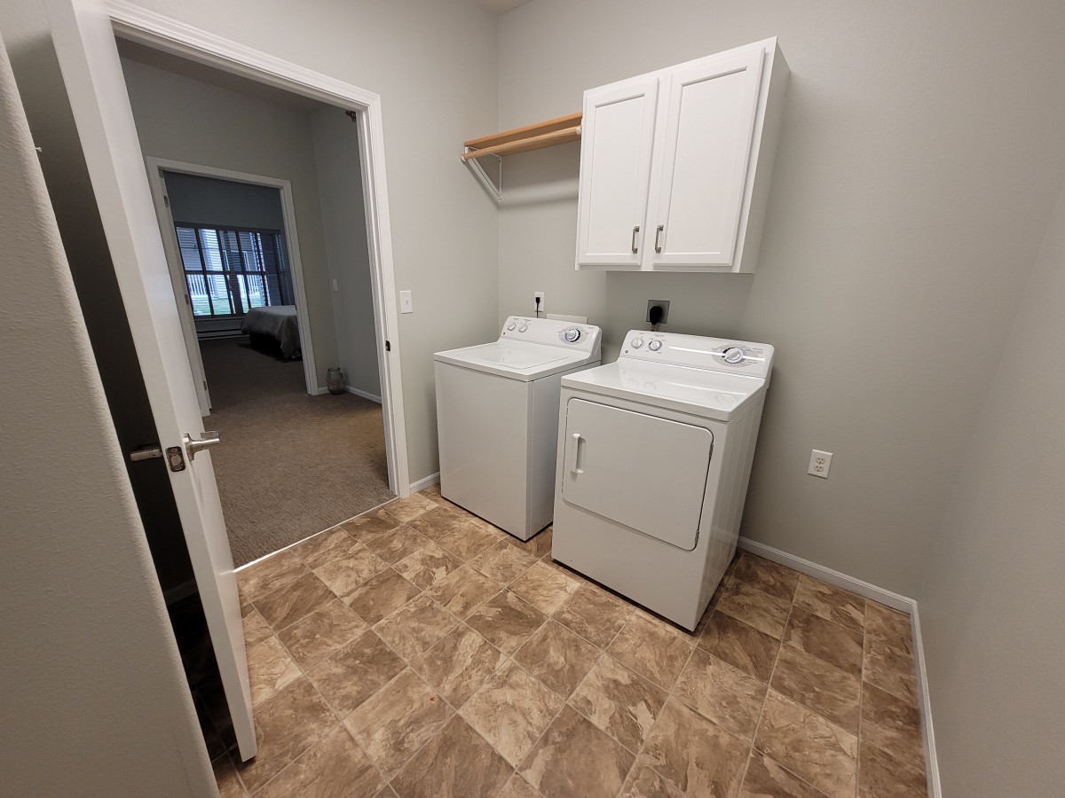 A laundry room featuring a washer and dryer, with cabinets and shelving above.