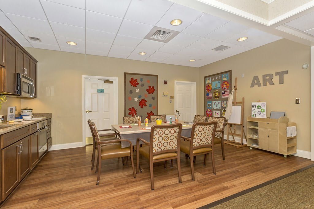An activity room with a table and chairs surrounded by art supplies and decorations.