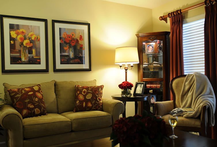 A cozy living room with a sofa, artwork, and a warm lamp illuminating the space.