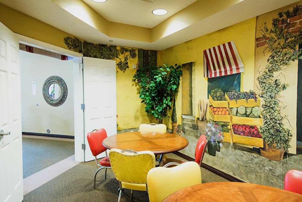 A cozy dining area with colorful chairs and a vintage mural on the wall.
