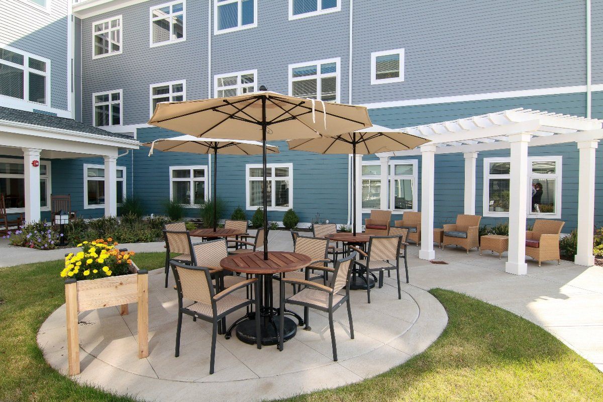 Outdoor patio area with tables, chairs, and umbrellas in front of a building.