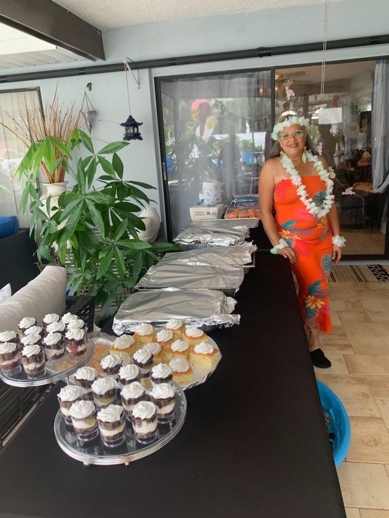A woman in traditional attire stands by a table with cupcakes, ready for the celebration.