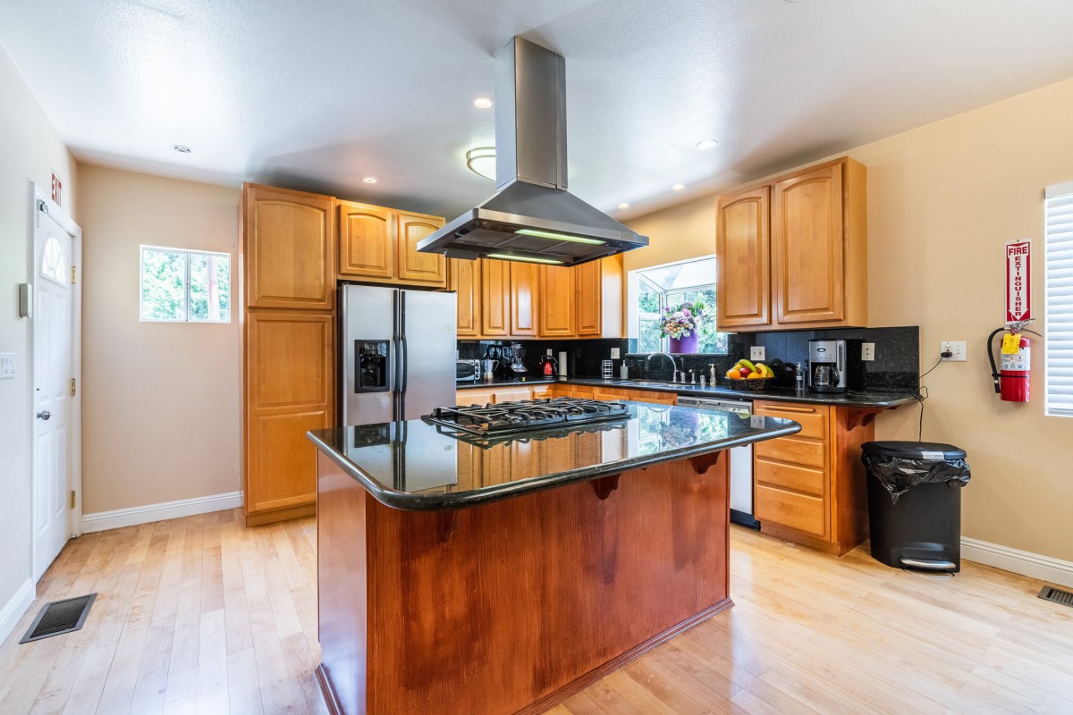 Modern kitchen with wood cabinets, a central island, and stainless steel appliances.