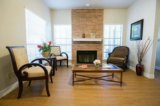 A cozy living room featuring a brick fireplace, comfortable armchairs, and a wooden coffee table.