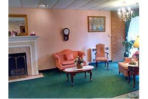 A vintage living room with classic furniture, a clock on the wall, and a fireplace.