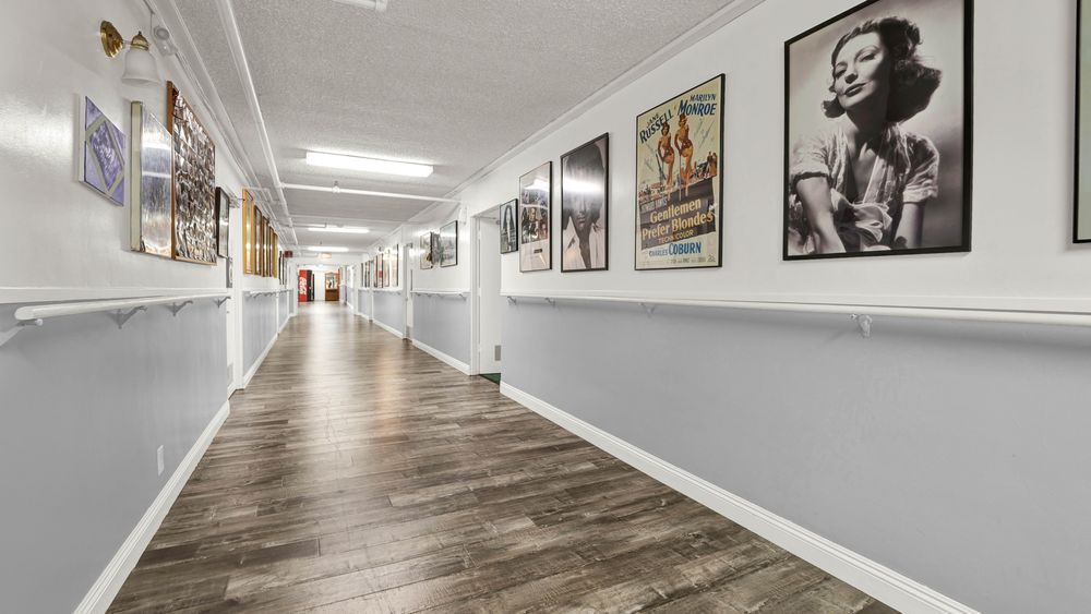 A long hallway adorned with framed posters and modern wooden flooring.
