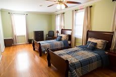 A cozy bedroom featuring twin beds with plaid bedding and wooden furniture.
