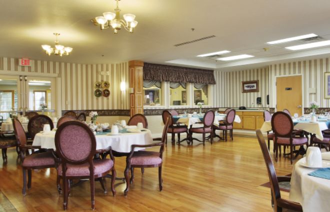 A spacious and elegantly decorated dining room with neatly arranged tables and chairs, featuring wooden flooring and stylish lighting fixtures.