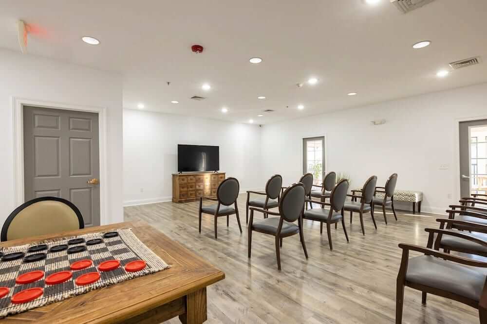 A minimalist conference room with arranged chairs and a television.