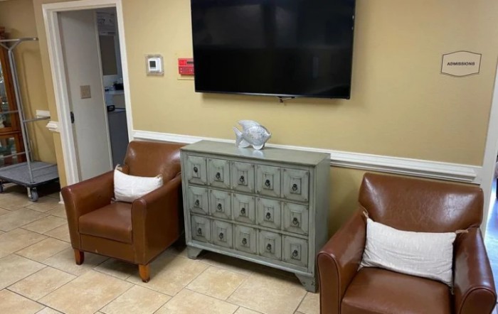 A cozy living room with a flat-screen TV, two leather armchairs, and a decorative console table.