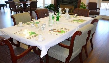 A dining table set for a meal, featuring a white tablecloth, glassware, and decorative centerpieces.