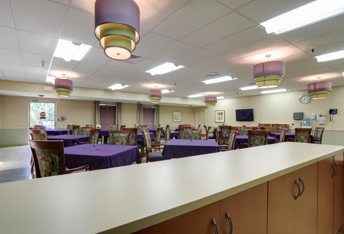 A modern dining area featuring tables with purple tablecloths and stylish lighting.