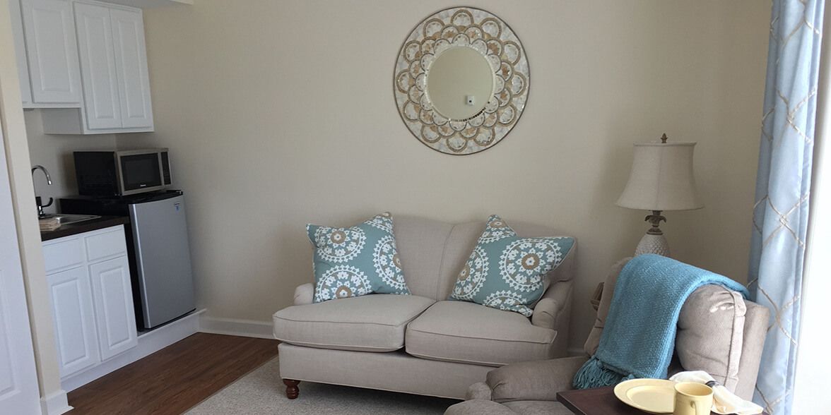 A cozy living room with a neutral sofa and patterned cushions, complemented by a decorative wall mirror.