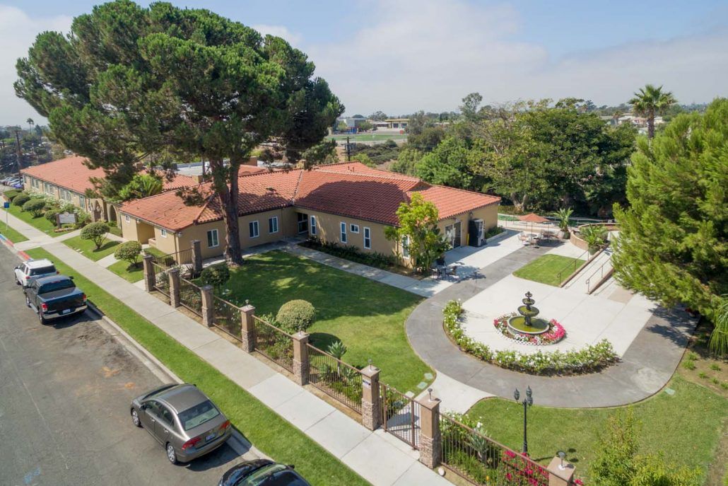 Aerial view of a luxury suburban house with a landscaped garden and circular driveway.
