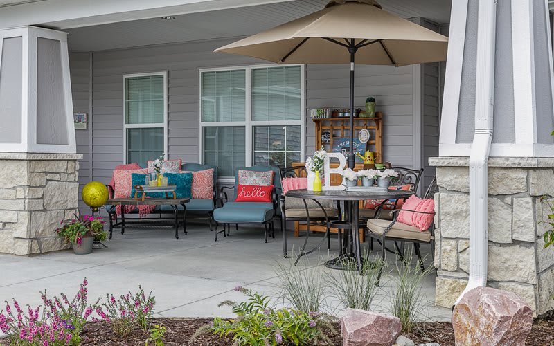 A cozy patio setup featuring colorful seating, a dining table with an umbrella, and decorative elements.