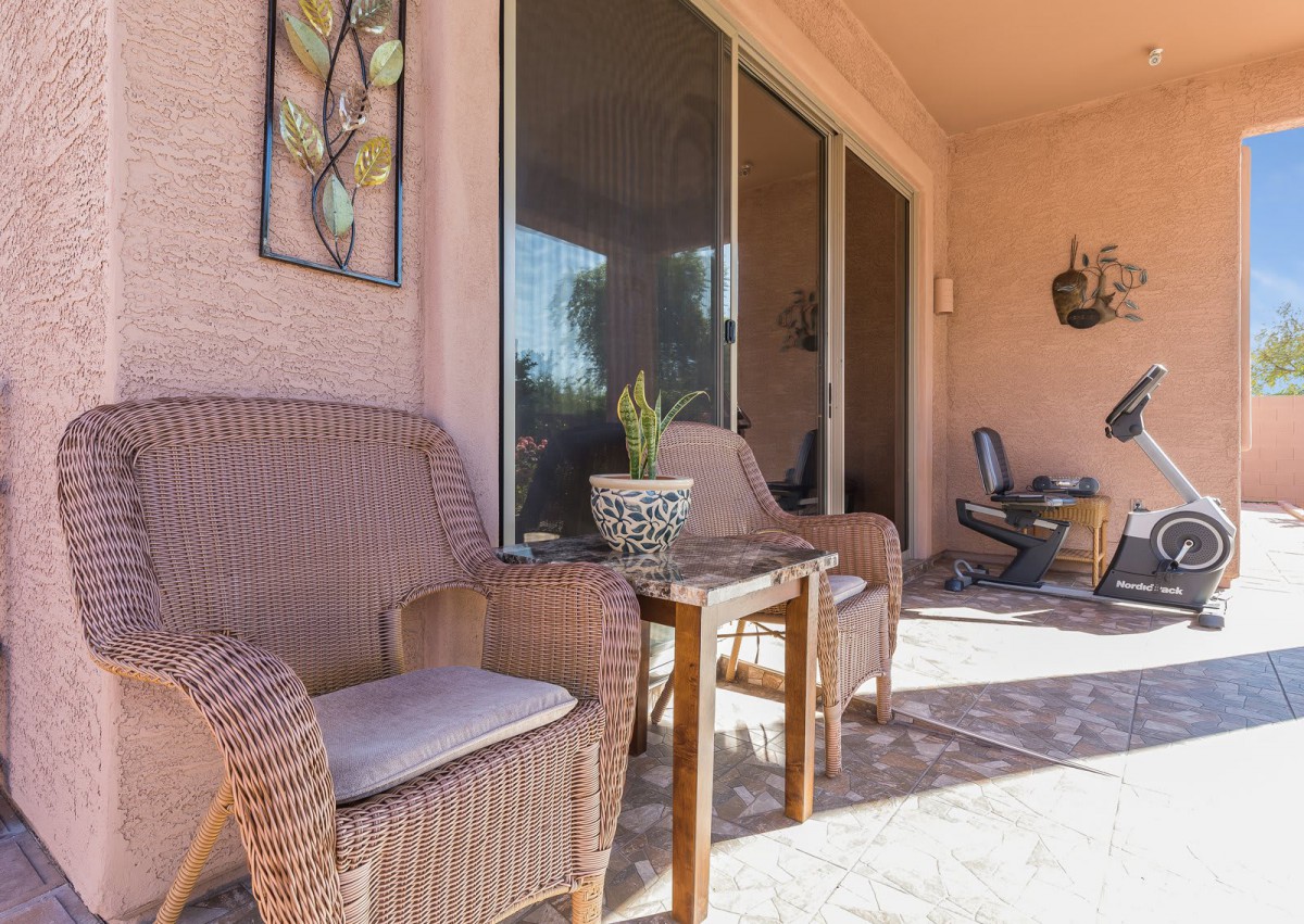 A cozy patio area with wicker chairs, a small table, and decorative elements basking in sunlight.